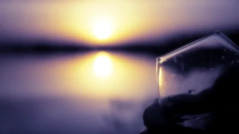 Two glass glasses with various drinks on a background of a decline at water are Stock Footage 76142809