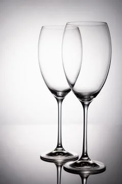Two glass goblet without wine on a thin leg stands on a mirror surface. Stock Photos