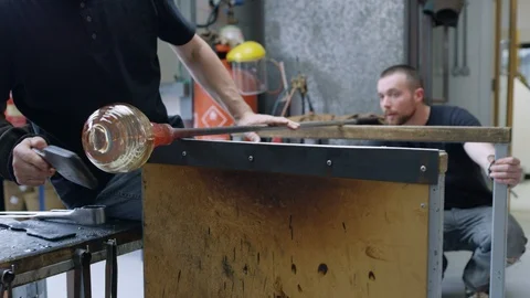 Two glassblowers shaping a glassware in workshop Video stock 107939449