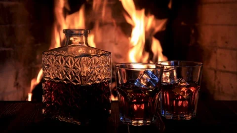 Two glasses and a decanter of whiskey near the fireplace 스톡 동영상 121312545