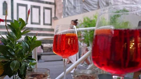 Two glasses of aperitif on the table with people passing by in the background Stock Footage 224315726