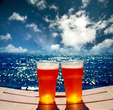 Two glasses of beer on a beach. Stock Photos