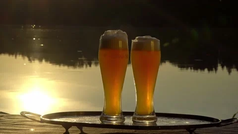 Two glasses of beer  at sunset on a forest lake Stock Footage 139809927