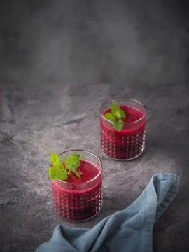 Two glasses of beetroot smoothie with mint leaves on dark table. Stock Photos