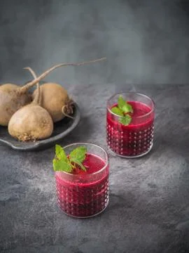 Two glasses of beetroot smoothie with mint leaves on dark table. Stock Photos