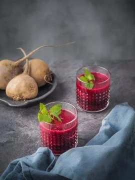 Two glasses of beetroot smoothie with mint leaves on dark table. Stock Photos