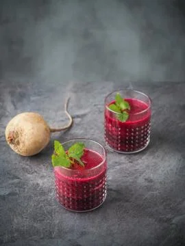 Two glasses of beetroot smoothie with mint leaves on dark table. Stock Photos