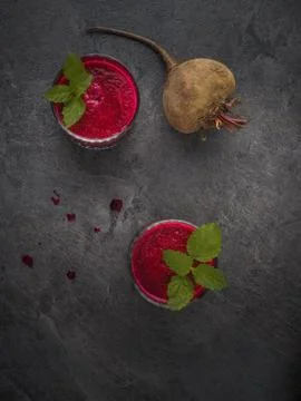 Two glasses of beetroot smoothie with mint leaves on dark table. Overhead Stock Photos