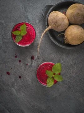 Two glasses of beetroot smoothie with mint leaves on dark table. Overhead Stock Photos