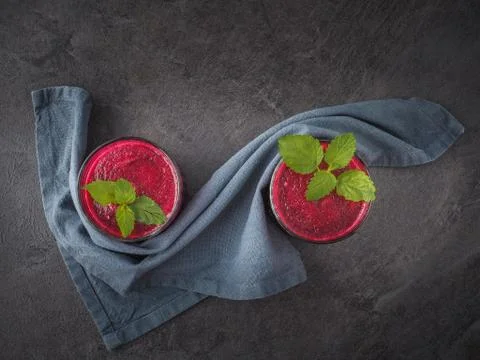 Two glasses of beetroot smoothie with mint leaves on dark table. Overhead Foto stock