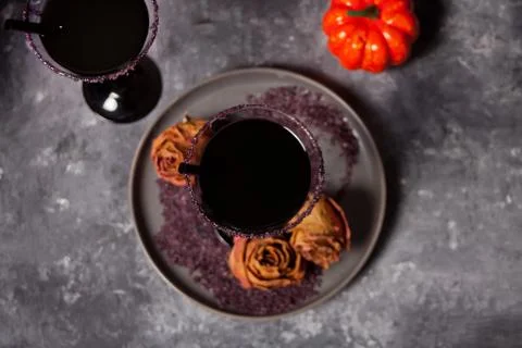 Two glasses with black cocktail, dried roses, pumpkin for Halloween party on  Photos