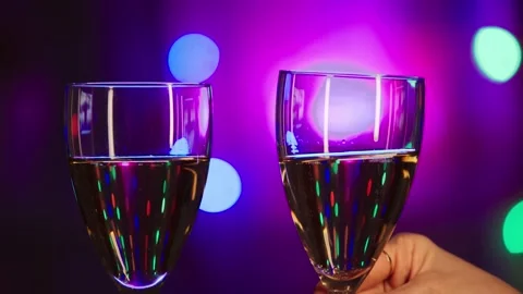 Two glasses of champagne on a background of colored lights Stock Footage 259746633