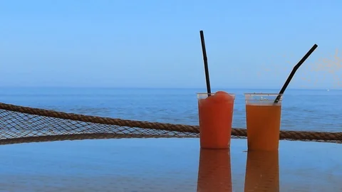 Two glasses of cocktail stand on a table in a bar near the seashore Stock Footage 114325557