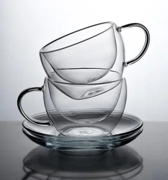 Two glasses for coffee or tea, standing on top of each other on a gray Stock Photos