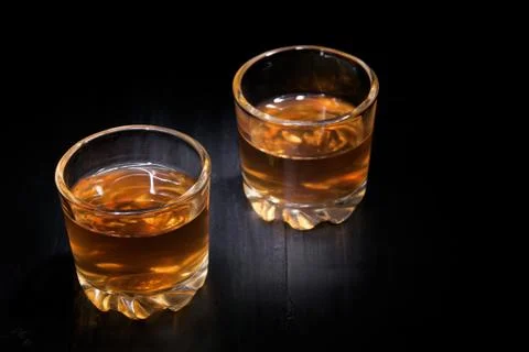 Two glasses of cognac on a black tree Stock Photos