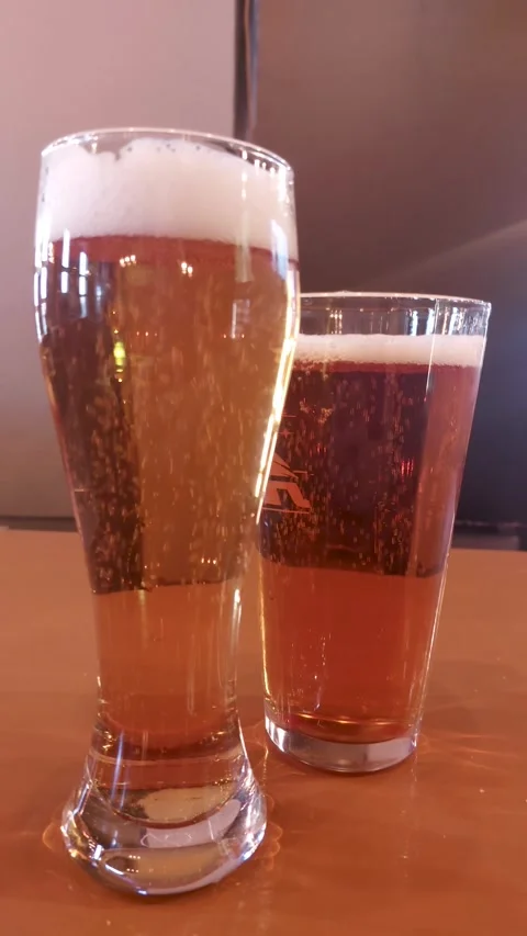 Two glasses of cold beer with foam on wooden table Stock Footage 337453123