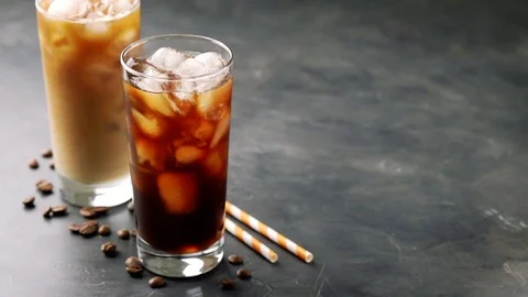 Two glasses of cold coffee on a dark background. In a tall glass with ice pour. Stock Footage 89781093