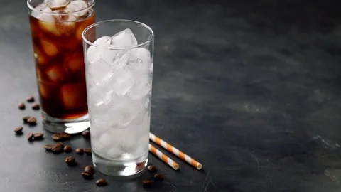 Two glasses of cold coffee on a dark background. In a tall glass with ice pour Stock Footage 89781621