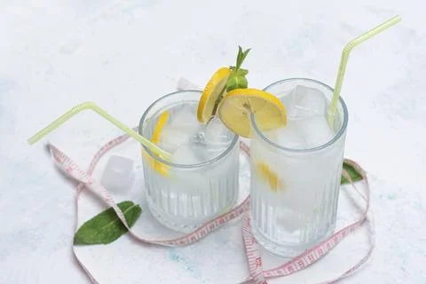 Two glasses of cold diet lemonade with lemon wedges, mint and ice cubes arr.. Stock Photos
