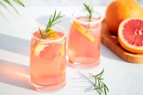 Two glasses with a fresh, cold summer cocktail of grapefruit and ice, garnished Stock Photos