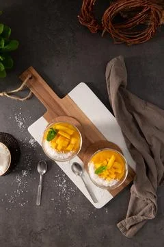 Two Glasses of Fresh Mango Mousse Topped with Shredded Coconut and Mint Leave Stock Photos