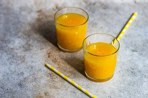 Two glasses of freshly squeezed orange juice with drinking straws Stock Photos