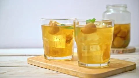 Two glasses of ginger lemon tea on wooden board with jar behind Stock Photos