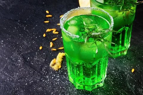 Two glasses of green liquid on dark surface with lemon slices Stock Photos