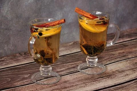 Two glasses of herbal tea with a slice of lemon and a cinnamon stick on a w.. Stock Photos