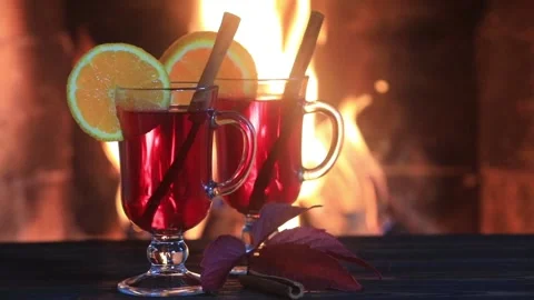 Two glasses of hot mulled wine with spices on wooden table against fireplace. Stock Footage 96017114