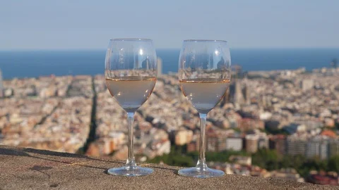 Two glasses of light wine stand at parapet, blurred cityscape on background Stockbeeldmateriaal 103384097