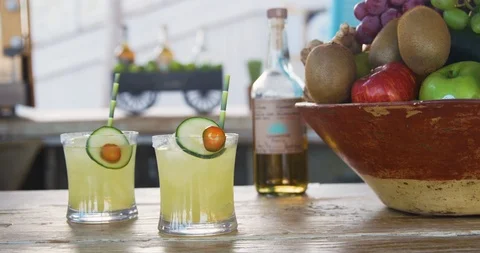 Two glasses of mojito cocktail with slice of cucumber on wooden table Stock Footage 101198937