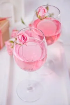 Two glasses with pink grape wine with rose flowers. Romantic dinner concept. Stock Photos