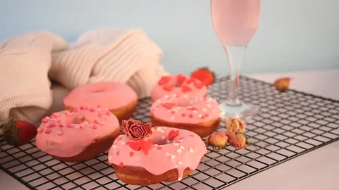 Two glasses with pink wine or champagne and pink doughnuts on the baking rack Stock Footage 145122212