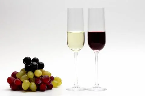Two glasses with red and white wine with grapes on a light background Stock Photos