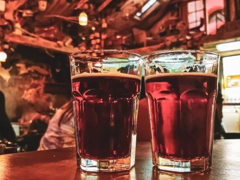 Two glasses of red beer or ale on a wooden table in a bar. Stock Photos