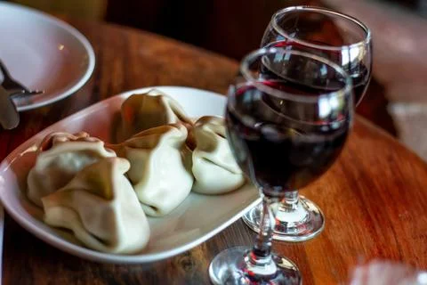 Two glasses of red wine against which Khinkali lie Stock Photos