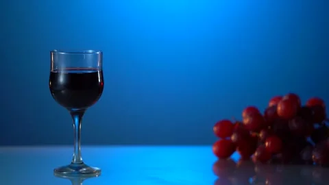 Two glasses of red wine. Alcoholic drink in a glass. A bottle of wine. Blue Stock Footage 240575843