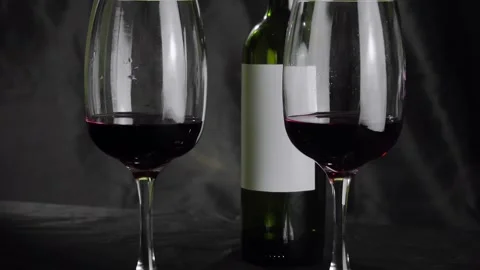 Two glasses of red wine and a bottle are on the table. Black background Stock Footage 146609732