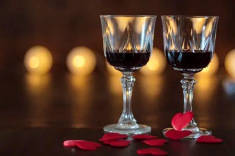 Two glasses of red wine and hearts on a wooden table Stock Photos