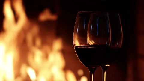 Two glasses of red wine on the background of fire in the fireplace. Holiday Stock Footage 232779758
