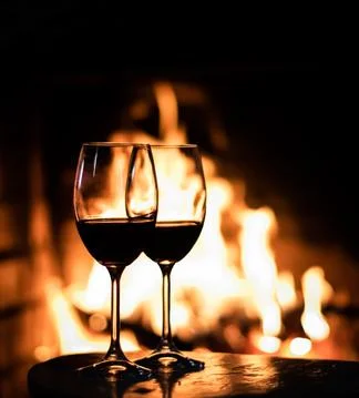 Two glasses of red wine on the background of fireplace lights Stock Photos