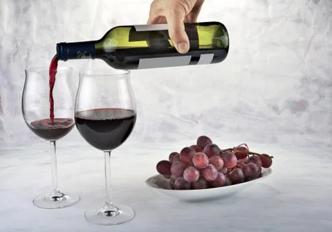 Two glasses of red wine with bottle and grapes Stock Photos