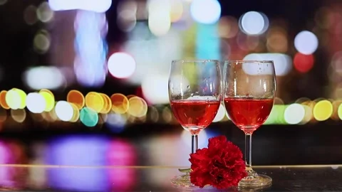 Two glasses of red wine, carnation flower with colourful blurred city night b Stock Footage 151626028