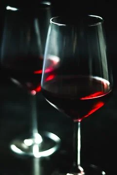 Two glasses of red wine casting reflections, creating an intimate, elegant,.. Stock Photos