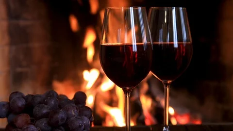Two glasses of red wine with cheese and grapes near the fireplace. Stock Footage 121311231