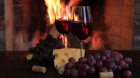 Two glasses of red wine with cheese and grapes near the fireplace. Stock Footage 163547921