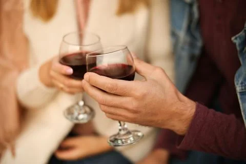 Two glasses of red wine close-up in hands outside the house. Man and woman in Stock Photos