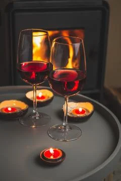 Two glasses of red wine front of fireplace. Romantic light Stock Photos