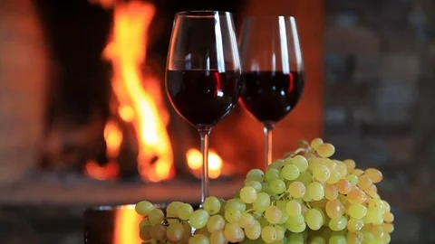 Two glasses of red wine with grapes near the fireplace in the evening Stock Footage 81661424